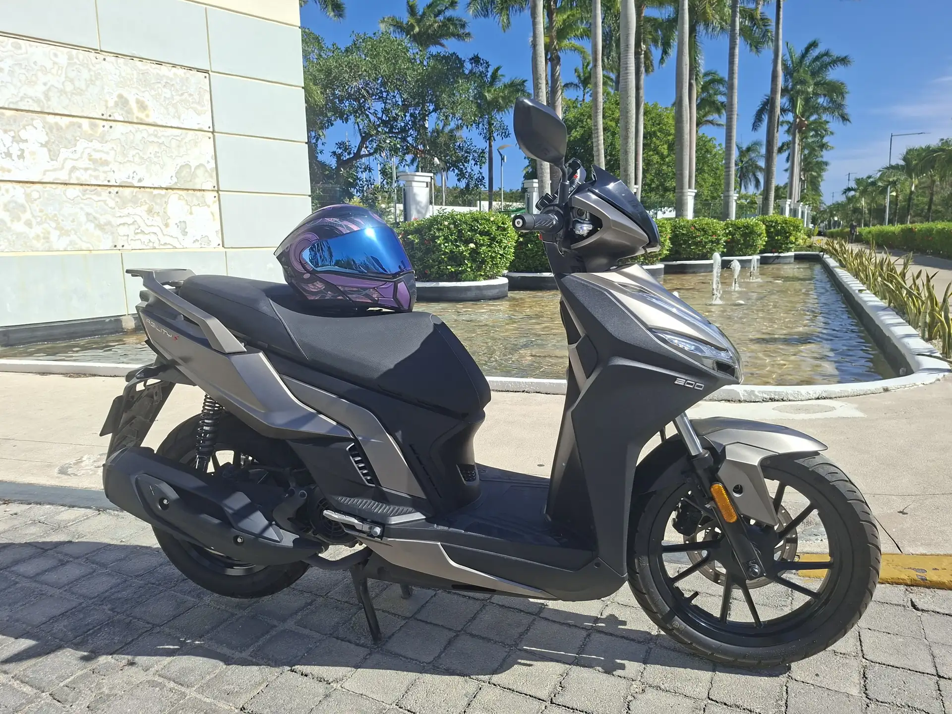 Kymco Agility S200i rental scooter with a helmet at a resort in Playa del Carmen