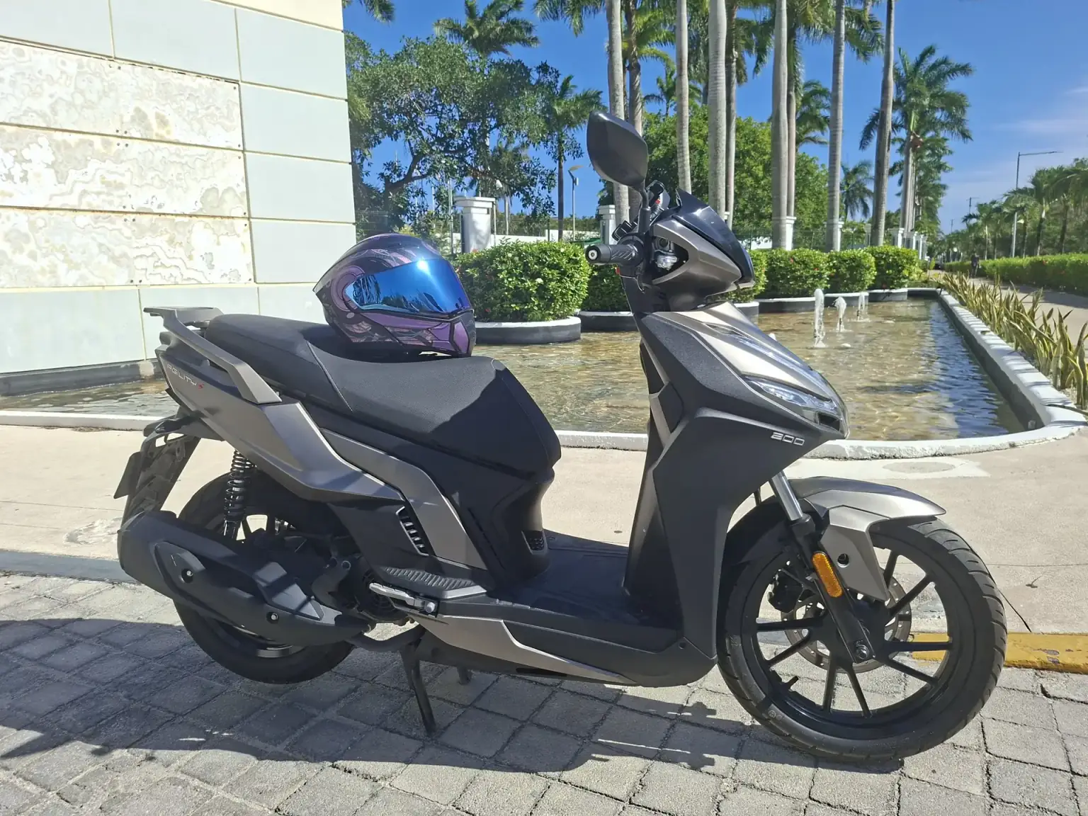 Kymco Agility S200i rental scooter with a helmet at a resort in Playa del Carmen